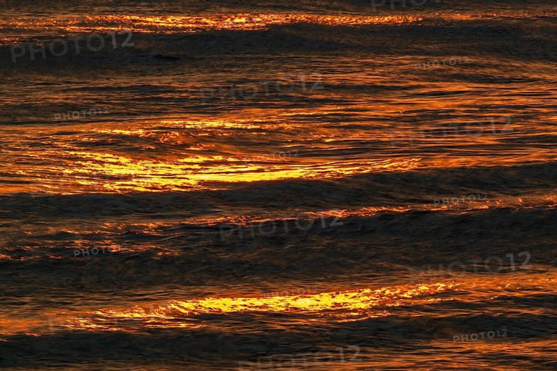Setting sun colors the sea and small waves golden, Houvig Beach, North Sea, Denmark