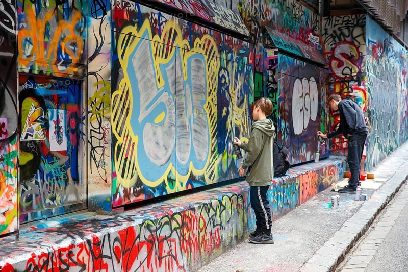 Young graffiti artists at work on street art in Rutledge Lane, Melbourne, Victoria, Australia