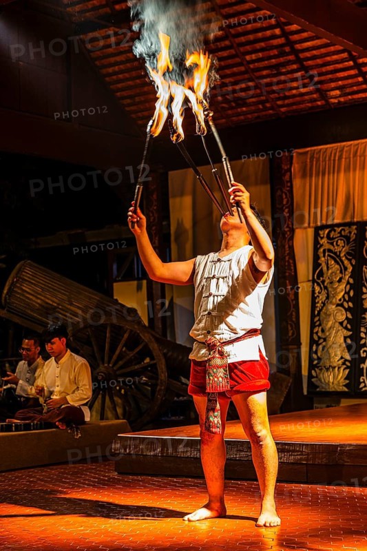 Young Thai man in traditional clothing in a historic show with burning torches, Old Chiang Mai Cultural Center, Chiang Mai, Thailand