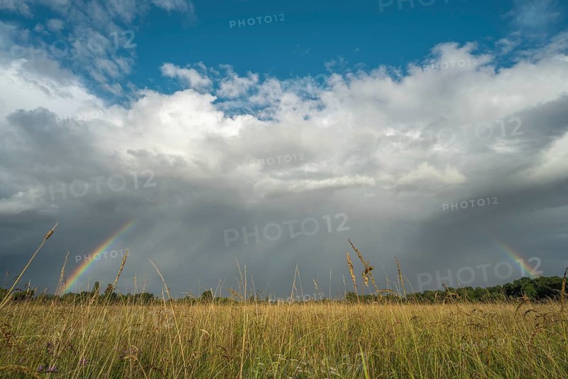 A rainbow appears in the cloudy sky over a field and bears witness to the traces of the recent storm in the countryside. Bas-Rhin, Alsace, France