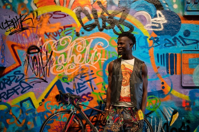 Young man, dark-skinned, African, smiling, posing in front of graffiti, legal, temporary graffiti in the graffiti tunnel, colorful, Leake Street Arches, London, England, Great Britain, Great Britain