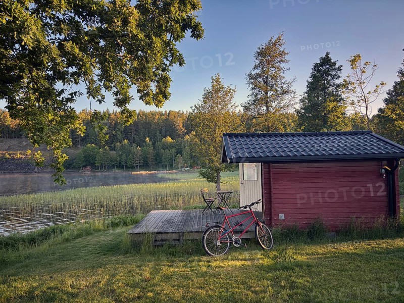 Little red hut with bike on a lake. wooden terrace in quiet, green forest, camping, vacation, Högsbyn, Högsbyn, Dalsland Canal, Mellerud Municipality, Sweden