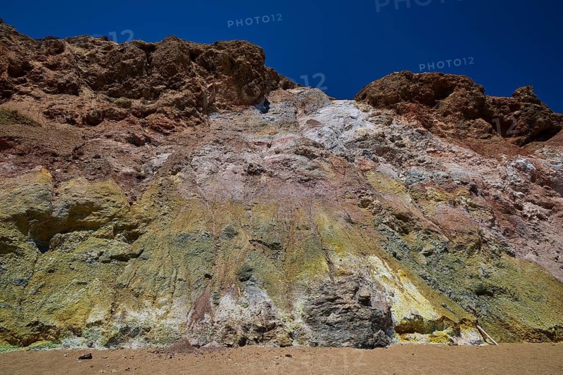 Colourful rock wall under clear blue sky, with various eroded layers, Paliochori beach, Paliochori, volcanic rock, copper, nickel, mineral salts, volcanic island, Milos, Cyclades, Greek islands, Greece
