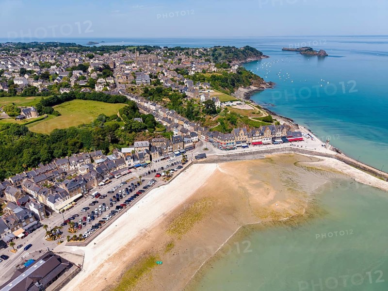 Aerial view of the picturesque fishing village of Cancale on the Emerald Coast. The picture shows the port area of Port de la Houle at low tide. The row of houses with numerous fish restaurants stretches along the shore. The region is world-famous for its oyster farming, Ille-et-Vilaine department, Brittany, English Channel, France