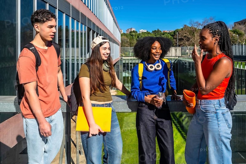 Group of multi ethnic students standing, smiling, and having a conversation on a modern university campus, representing education, friendship, and diversity in a college setting