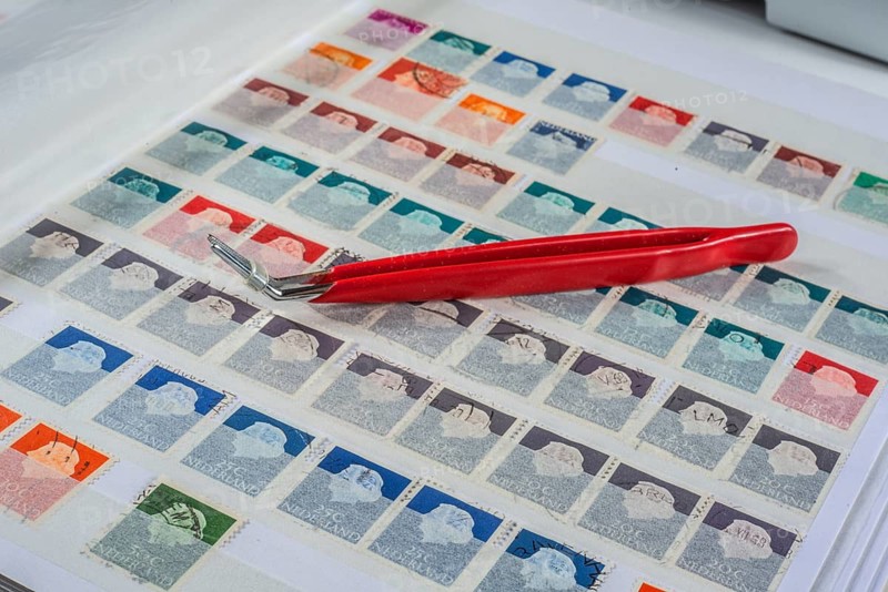 Philately, tweezers on album page with Dutch stamps