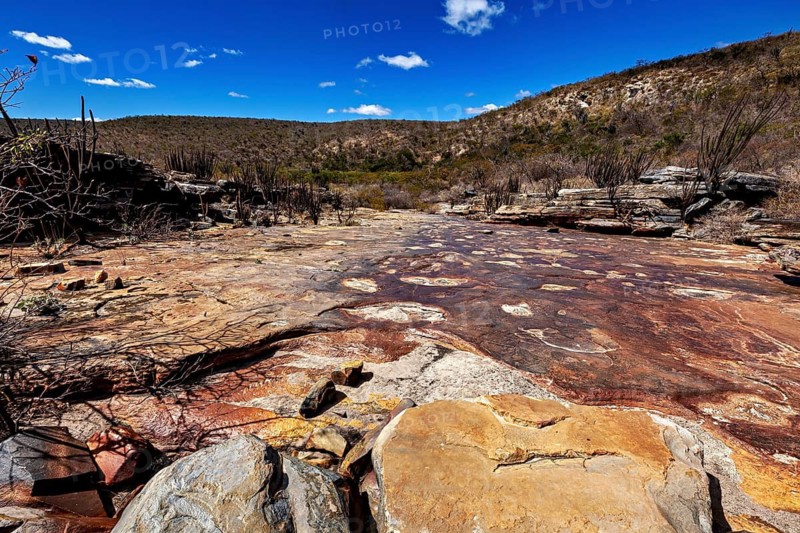 Brown and rust-red stones in a sunlit, vast desert landscape, the thornshrub savanna in the Caatinga countryside in the federal states of Pernambuco and Bahia in Brazil