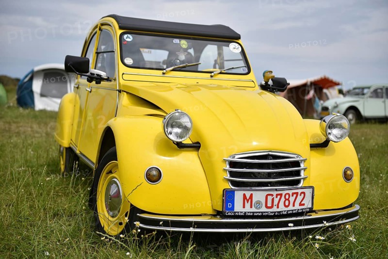 A yellow Citroën 2CV stands in a meadow surrounded by tents, radiates classic charm, Citroën 2CV at a duck meeting in Kropp, Schleswig-Holstein, Germany