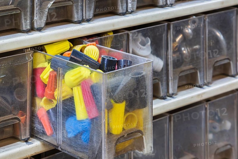 Opened plastic parts drawers showing twist on yellow, black, blue and red electrical wire connecting caps or wire nuts, Quebec, Canada