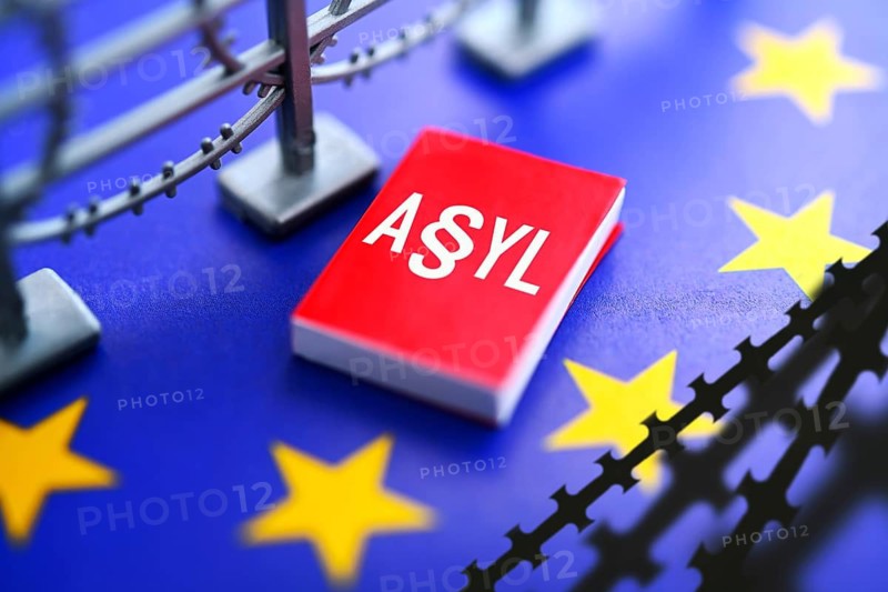 Book with asylum lettering on EU flag with barbed wire, European asylum reform, photo montage +++ editorial use only