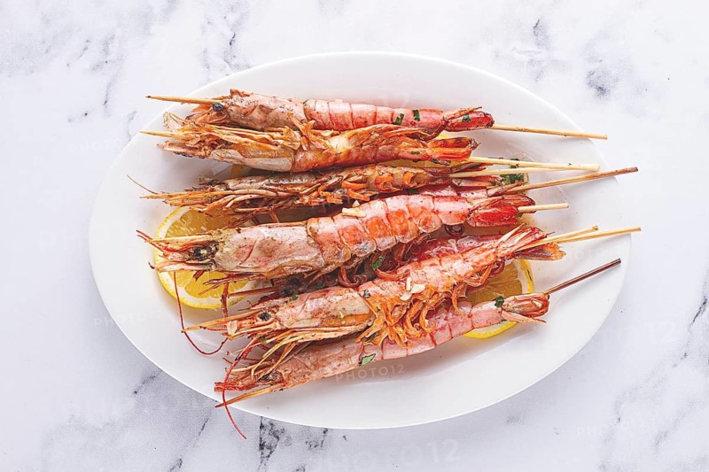 Freshly grilled prawns served, on a white platter, with lemon slices, for a delicious seafood experience
