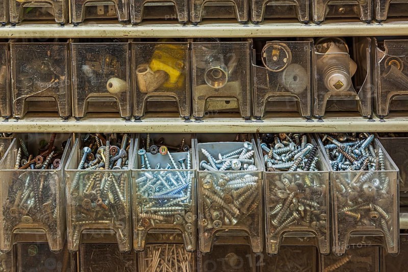 Opened row of plastic parts drawers in cabinet showing mixed phillips, robertson and flathead screws, Quebec, Canada