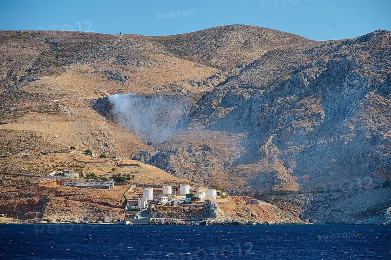 Waste incineration plant, tanks, dry mountain landscape with industrial plant and blue sea in the foreground, Pothia, main town, port, Kalymnos, Sponge Diving Island, Dodecanese, Greek Islands, Greece