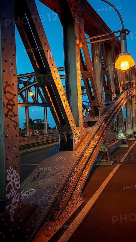 Steel bridge, with graffiti and lanterns in warm evening light, heritage-protected Bösebrücke, Bornholmer Straße, Berlin