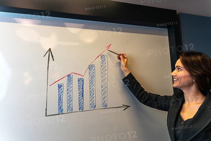 Confident businesswoman smiling at positive growth chart during corporate presentation