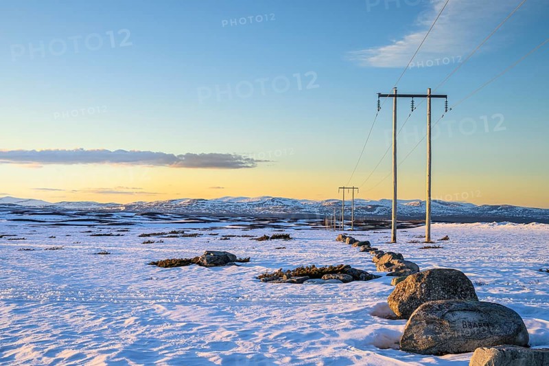 Ljungdalen, Jämtlands län, Sweden, snowy expanse with rocks and power poles, sunset bathes the landscape in warm light, Flatruet, Berg, Härjedalen Län, Sweden