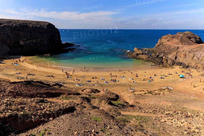 Lanzarote, Canary Islands, Spain, Europe, Playas de las Papagayo, bathers relax on a sunny beach surrounded by cliffs with clear, blue water