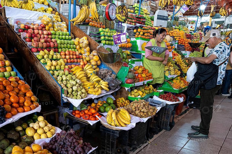 A friendly smiling market woman from the indigenous population group sells exotic fruits at her stand, market hall, weekly market market, Arequipa, southern Peru, South America