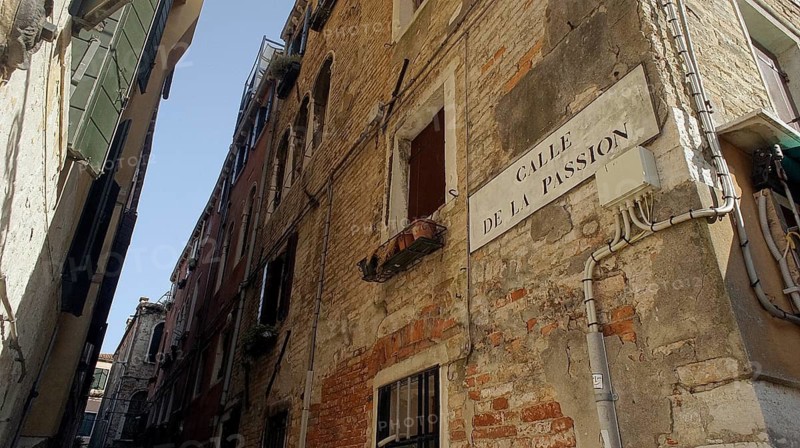 Narrow alley in Venice, alleyway sign 'Calle de la Passion' with old brick architecture and flower pots on a window, Venice, Veneto, Italy