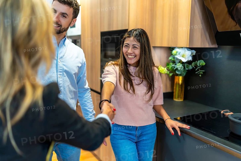 Young couple meeting with a sales representative, shaking hands in a modern kitchen showroom, contemplating new home design and renovation possibilities