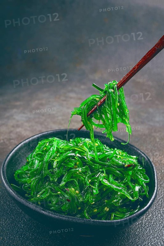 Chuka salad, made from fresh seaweed, with sesame dressing, served in a black bowl, with chopsticks
