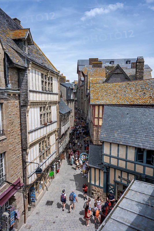Tourists flock through a medieval alley surrounded by traditional half-timbered houses within the fortress walls of Mont-Saint-Michel, tourist attraction, UNESCO World Heritage Site, Pontorson, Manche department, Normandy, France