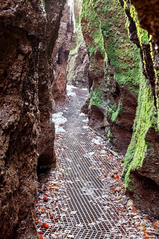 A narrow path leads through rough, moss-covered gorge walls and enchants with its natural roughness, The Dragon Gorge near Eisenach in Thuringia