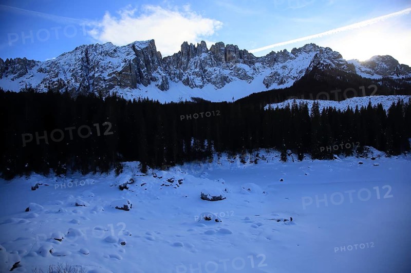 Snowy mountains in the background with dark forest in the foreground under clear blue sky, Pragser Wildsee, Lago di Lake Prags, frozen mountain lake in winter, Prags, Lake Prags, South Tyrol, Italy