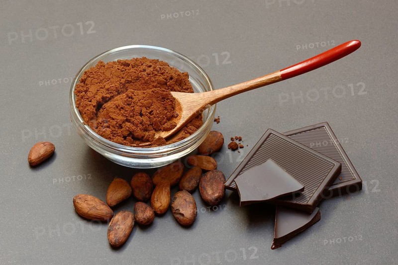 Cocoa powder in glass bowl, cocoa beans and dark chocolate