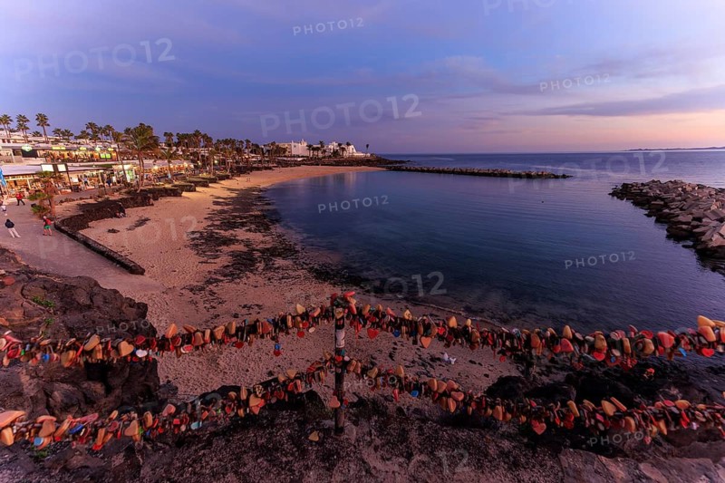 Lanzarote, Canary Islands, Spain, Europe, Playa Blanca, Love Castles, Beach View with Love Locks and a Distant Town at Dusk