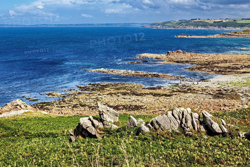 Rocky coastline with wavy sea and partly cloudy sky, the coastal landscape near Cleder in Brittany