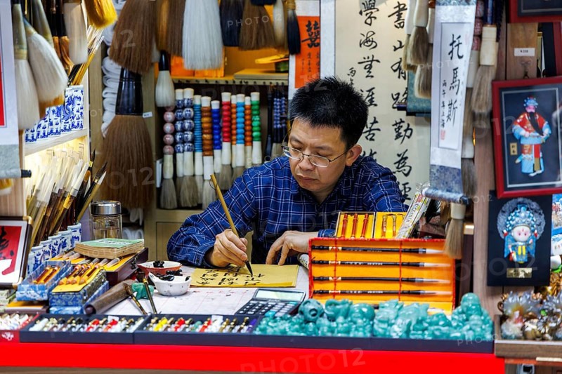 Calligrapher writes Chinese characters at art stall, Old Town Bazaar, Shanghai, China