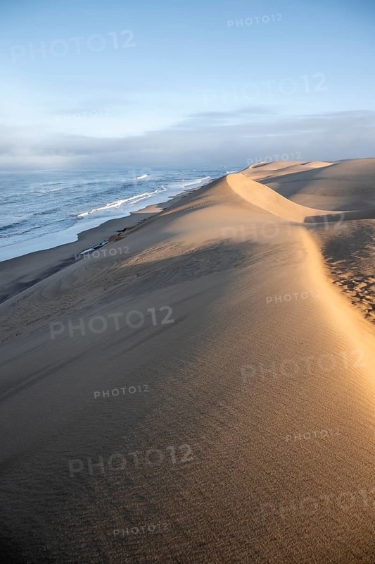Sand dunes in morning light, view of Atlantic coast and sea, Sandwich Harbour, impressive desert landscape, Namib Naukluft Park, Namibia