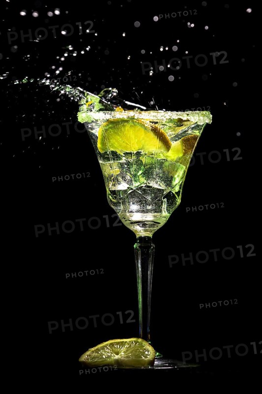 A sparkling cocktail glass with lemon slices and ice cube cubes against a black background