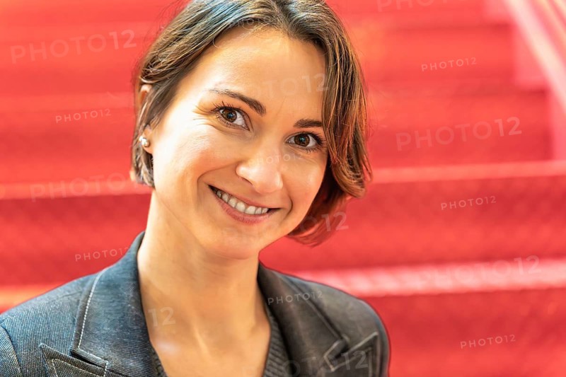 Confident IT professional woman smiling at camera, red industrial bokeh background