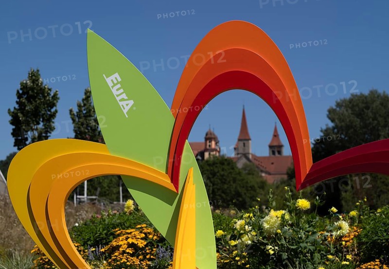 EurA AG logo on a symbol, a sculpture of a flower, with the Protestant Town Church and the monastery's collegiate church – now St Vitus' Basilica – in the background, State Garden Show 2026, Ellwangen (Jagst), Baden-Württemberg, Germany