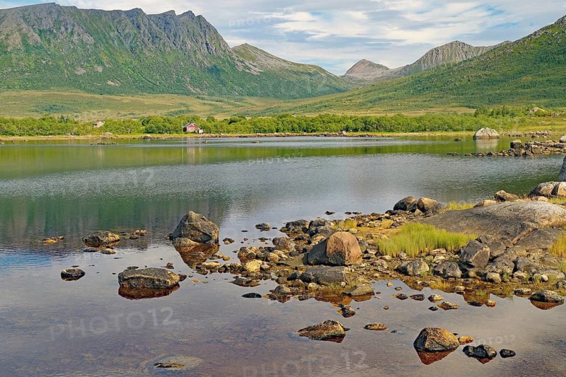 Rocks are scattered on a quiet lake with mountain views, Andoeya, Vesteralen, Norway