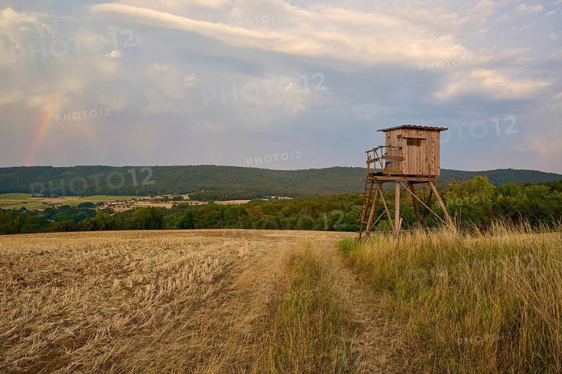 A raised seat in a field with a rainbow in a cloudy sky, summer, Großheubach, Miltenberg, Spessart, Bavaria, Germany