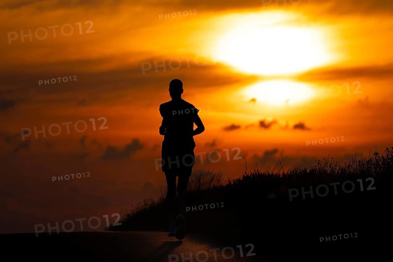 A female jogger runs along a Feldberg near Frankfurt am Main in the morning just after sunrise, Frankfurt am Main, Hesse, Germany