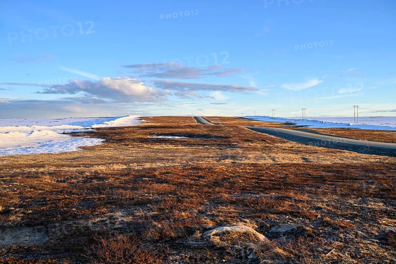 Storsjö Kapell, Jämtlands län, Sweden, A flat, open road on snow-covered terrain with low sun on Sweden's highest pass road, Flatruet