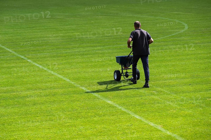 Groundsman spreads artificial fertilizer for grass on a football pitch in Lubin, Poland