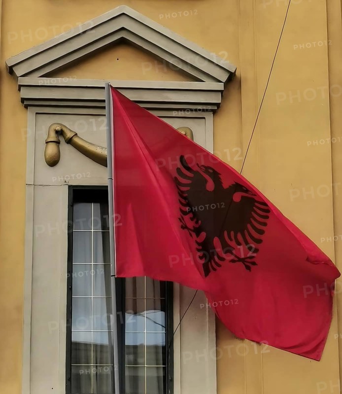 Albanian flag with black eagle attached to a yellow building, Albania