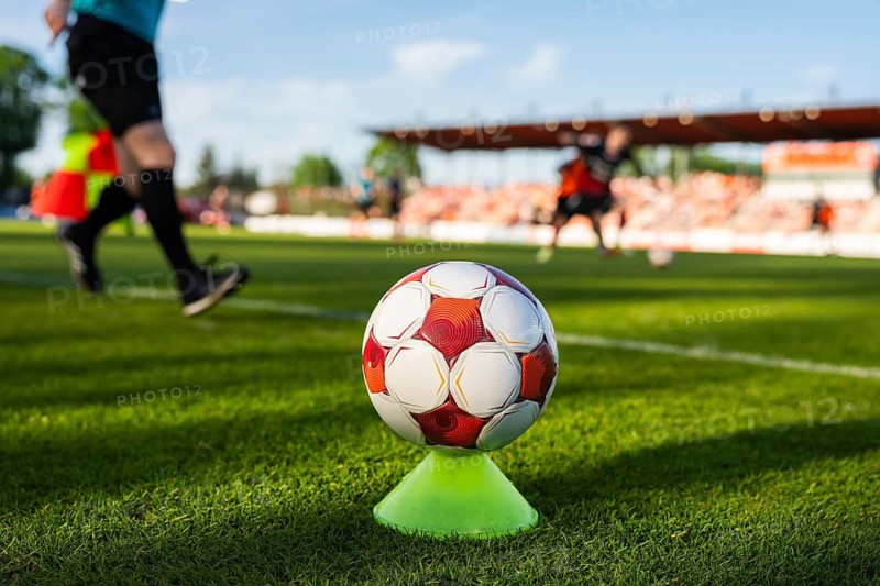Soccer ball on a training cone near the touchline during a football match with players and stadium blurred in background in Glogow, Poland