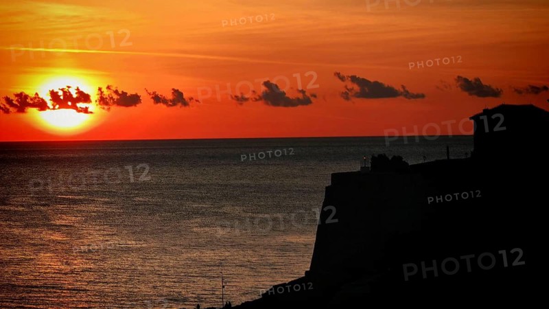 Sunset over sea with silhouette of cliffs and orange sky, Ulcinj, Montenegro