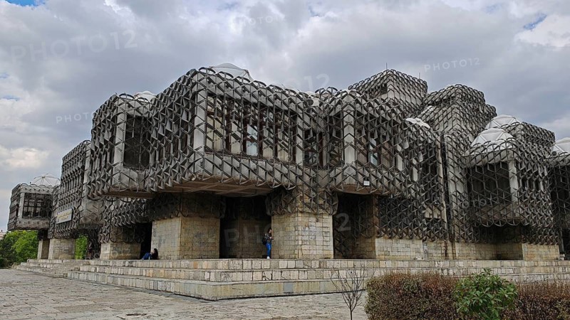 Modern building, National Library, Pjeter Bogdani, with unique stone grid design under cloudy sky, Pristina, Kosovo
