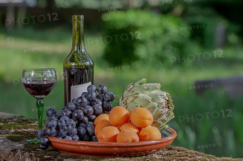 A plate of fruit and vegetables and a bottle of wine outdoors, Provence, France