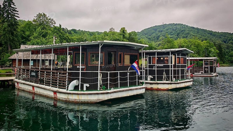 Wooden boats with the Croatian flag are moored on a calm lake against a wooded backdrop, ferry in Plitvice Lakes National Park, Croatia