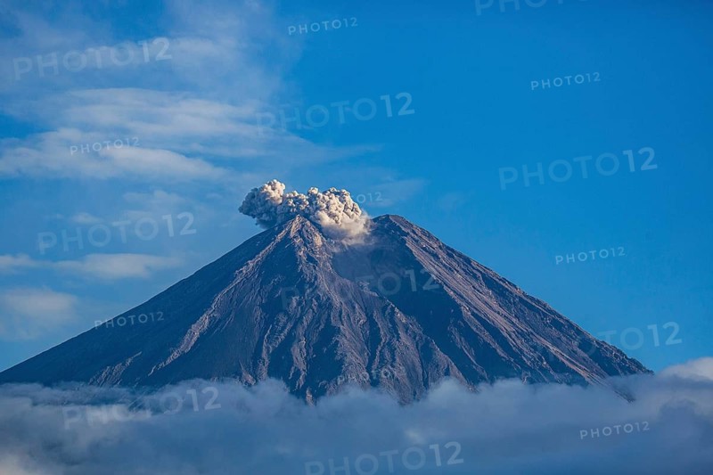 The volcano expels smoke from its summit, under a clear blue sky with surrounding clouds, Smoking Volcano, Sumatra, Jakarta, Indonesia