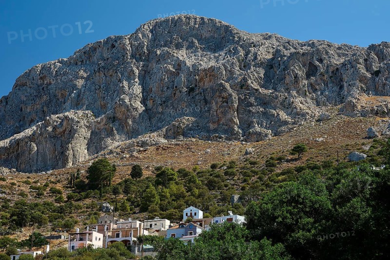 Melitsaches, small village at the foot of a large, rocky mountain under bright blue sky, Kalymnos, Sponge Diving Island, Dodecanese, Greek Islands, Greece