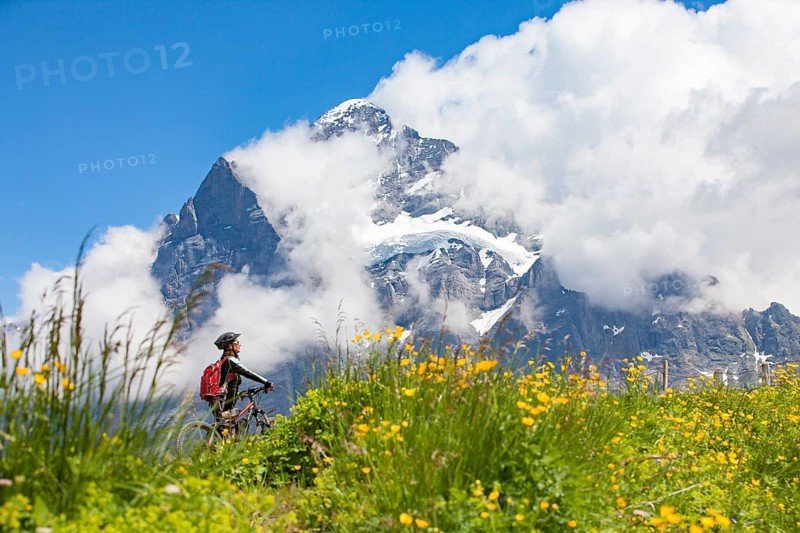 Woman riding her e-mountainbike below the Eiger northface, Jungfrauregion, Grindelwald, Bernese Oberland Switzerland